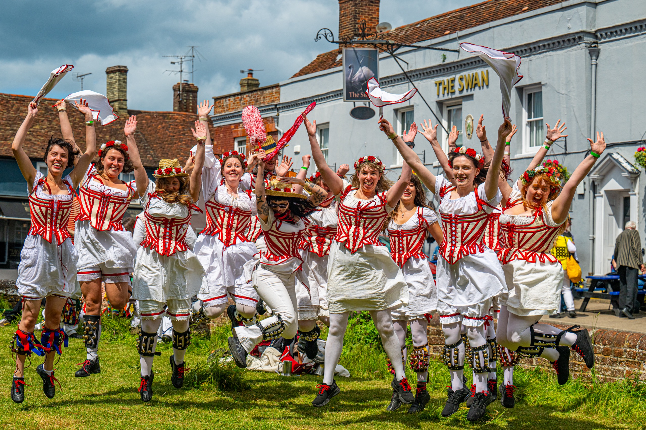 Morris dancing troupe jumping in celebration outside The Swan pub in Essex