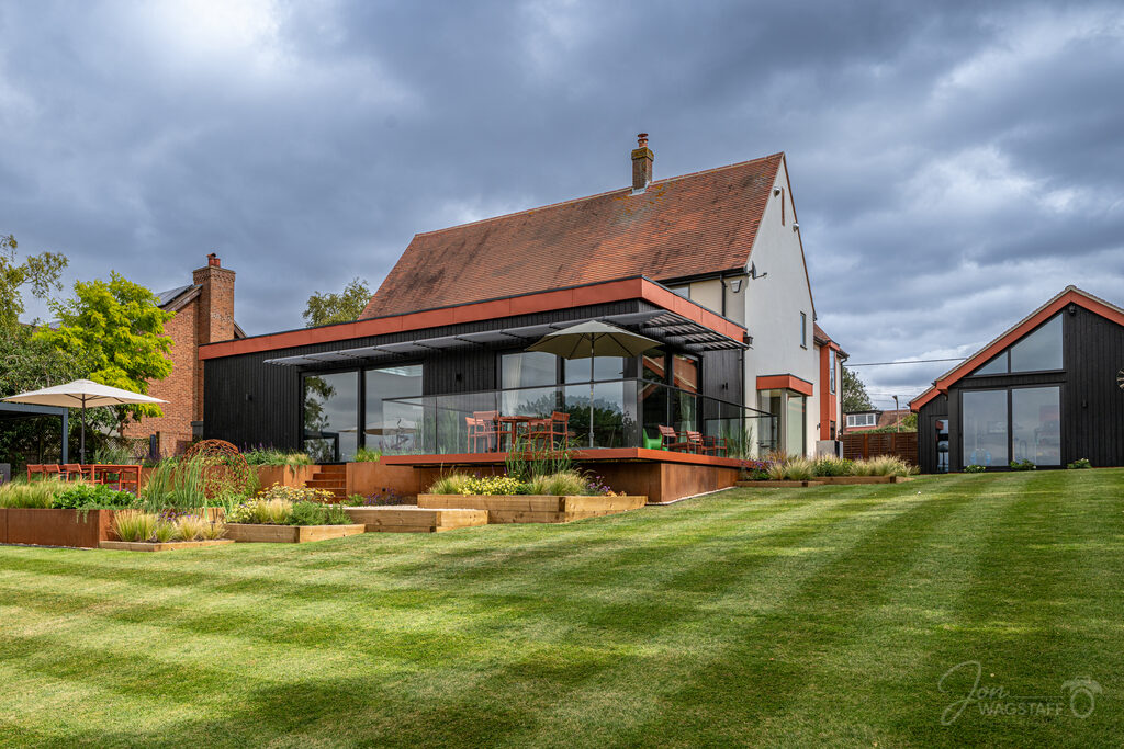 Exterior of a contemporary Essex home with black-clad extension and landscaped garden, photographed by Jon Wagstaff