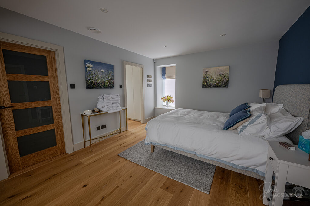 Bedroom with blue accent wall at Warwick House, photographed by Jon Wagstaff