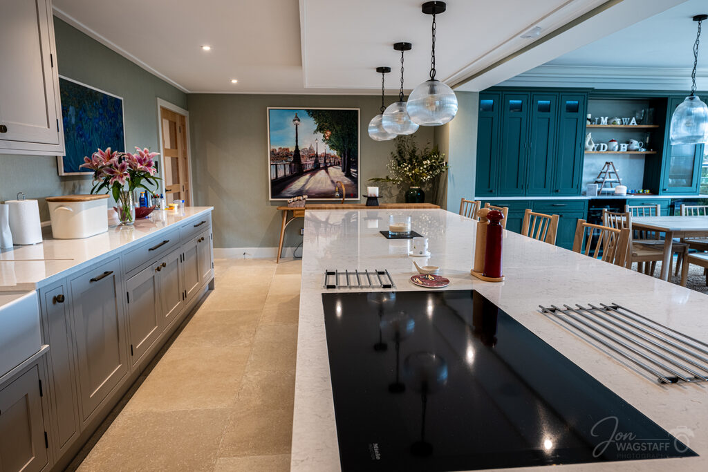 Open-plan kitchen with dark green cabinetry at Warwick House, photographed by Jon Wagstaff